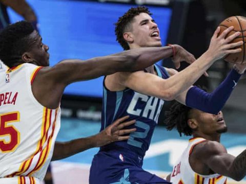 LaMelo Ball finishes at the rim under pressure from Atlanta Hawks' Clint Capela